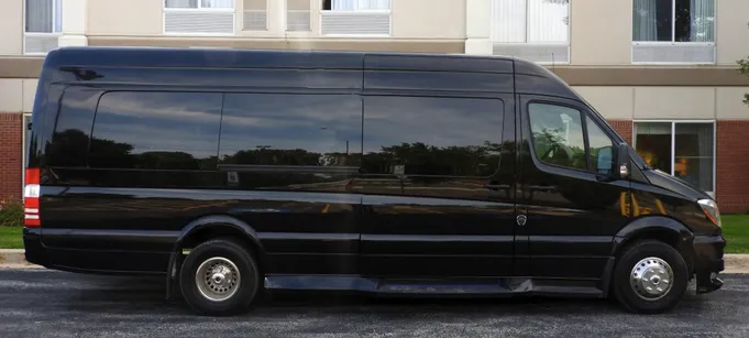 Black passenger van parked alongside a building, showcasing its spacious design, ideal for group travel or transportation services.