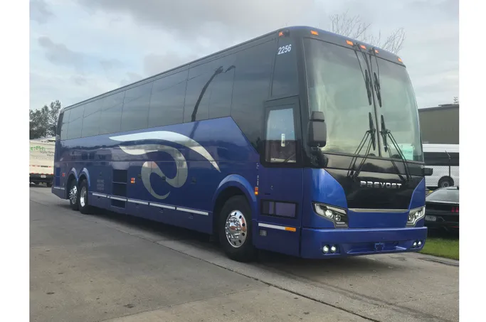 Blue motorcoach bus parked on a street, featuring modern design and sleek lines, illustrating transportation options for travel services.