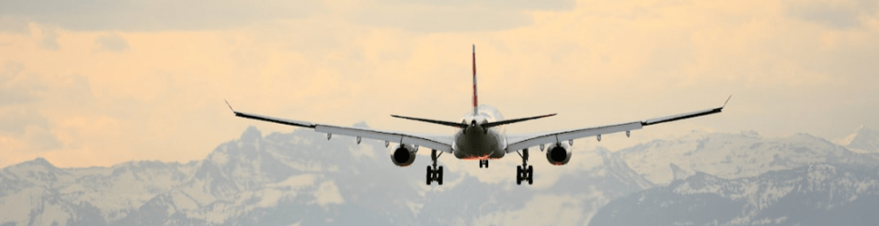 Airplane landing amidst snow-capped mountains under a cloudy sky, illustrating travel or aviation in a scenic setting.