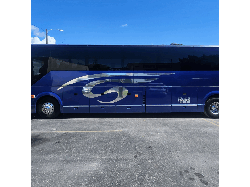 Blue luxury bus parked under a clear sky, featuring a sleek design and the company's name on the side, highlighting transportation services.