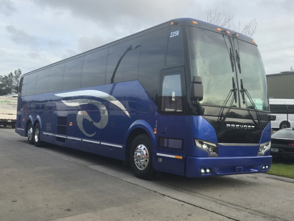Blue Prevost bus parked on a street, showcasing its sleek design and features. Relevant for travel and transportation contexts.